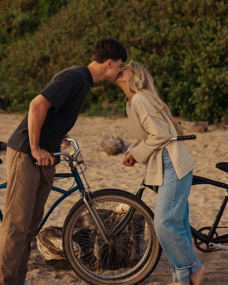 A male and female kissing while holding bikes